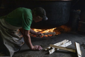 Feu de bois sous le chaudron en cuivre pour la fabrication du fromage Etivaz à l'alpage du Plan de l’Ouge, Etivaz, Pays d’en Haut. Suisse