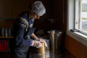 Une femme, fromagère, démoule et façonne un Geitost ou Brunost, fromage traditionnel norvégien, dans la fromagerie de l'alpage de Nupshadlene en Norvège