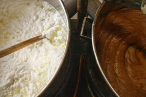Un chaudron rempli de petit-lait encore clair, en début de chauffage et un chaudron rempli de petit-lait de couleur brune en fin de cuisson, pendant la fabrication du Geitost ou Brunost, fromage traditionnel norvégien, dans la fromagerie de l'alpage de Nupshadlene en Norvège