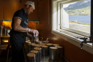 Un homme, fromager, coiffé d'une casquette, moule un Geitost ou Brunost, fromage traditionnel norvégien, dans la fromagerie de l'alpage de Nupshadlene en Norvège