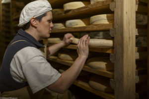 Une femme, fromagère, soigne un fromage dans la cave d’affinage de la ferme Chez Valentin à Foncine-le-Haut