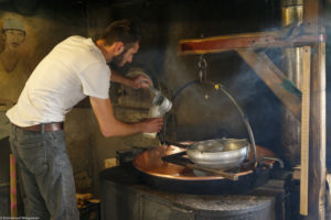 Un homme, fromager, prélève une mesure de lait dans le chaudron en cuivre dans la fromagerie de la ferme de Laisia dans le Haut-Jura