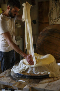 Un homme, fromager, change la toile d’égouttage du fromage qu’il vient de mouler dans la fromagerie de la ferme de Laisia dans le Haut-Jura