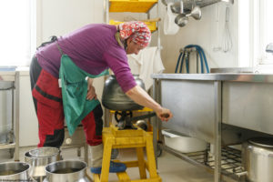 Une femme actionne la manivelle d'une baratte pour la fabrication de beurre fermier à Våler en Norvège.