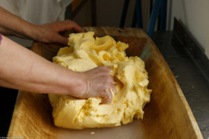 Extraction du babeurre et de l'eau de lavage résiduels dans un baquet en bois utilisé pour la fabrication de beurre fermier à Våler en Norvège.