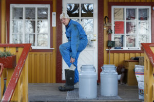 Une femme, éleveuse, enfile ses bottes devant la porte de sa ferme à Våler en Norvège.