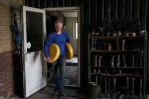 Un homme, fromager, transporte deux meules de fromage Boeren Goudse Oplegkaas à Rijpwetering aux Pays-Bas.