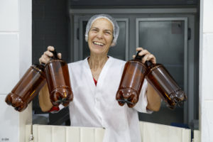 Une femme, fromagère, souriante, porte des bouteilles à lait en plastique sombre à Boa Vista do Incra au Brésil.